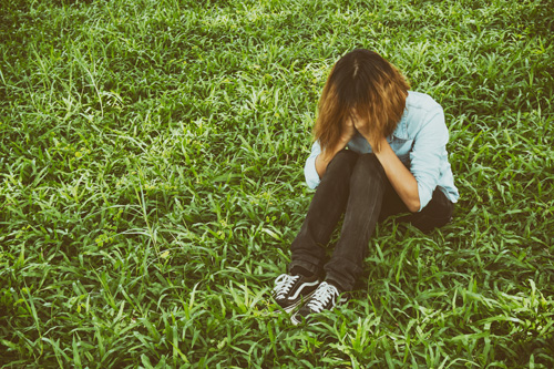 Mental Health - Girl Sitting On Grass With Head In Her Hands